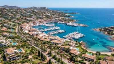Aerial view of an upscale Mediterranean coastal city featuring luxury villas, modern apartments, yacht marina, palm-lined boulevards